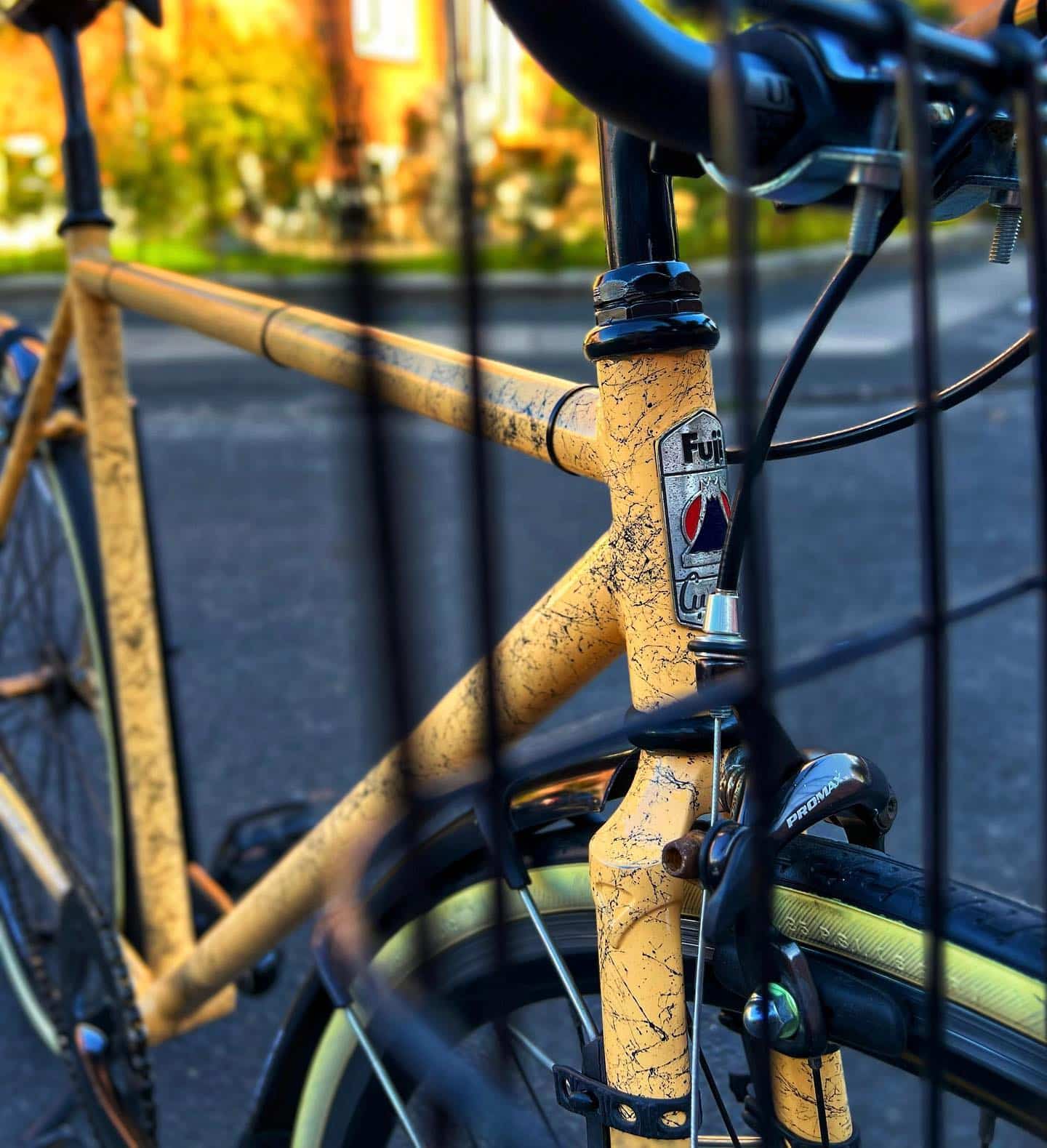 Cykel med gammelt, patineret gult stel parkeret udenfor